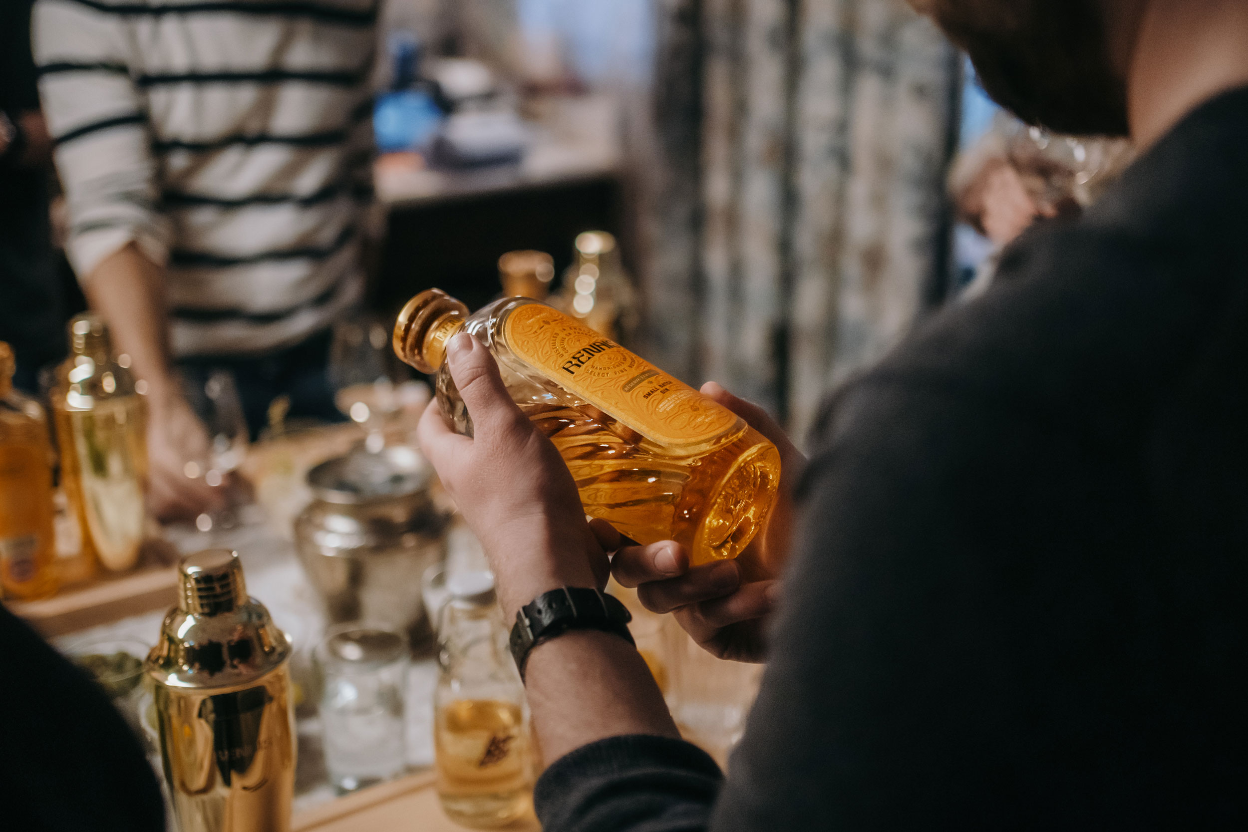 Person holding a bottle of whiskey, examining the label closely.