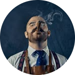 Man in a tie and apron smoking a cigar.