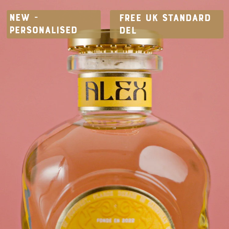 Glass bottle with personalized label reading 'Alex' against a pink background.