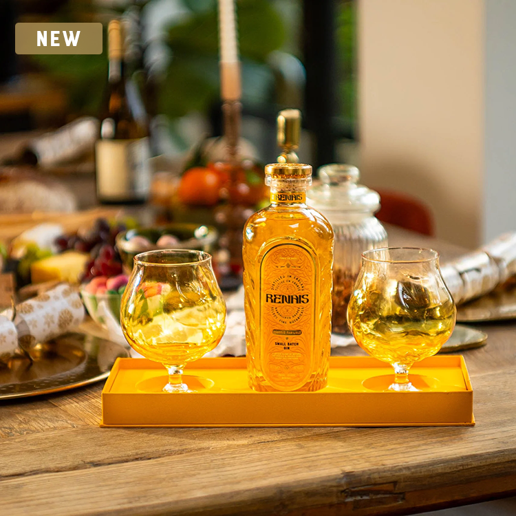 Bottle and two glasses of Reinnis whiskey on a wooden table.